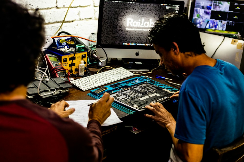 Technicians working on computer hardware at a repair bench